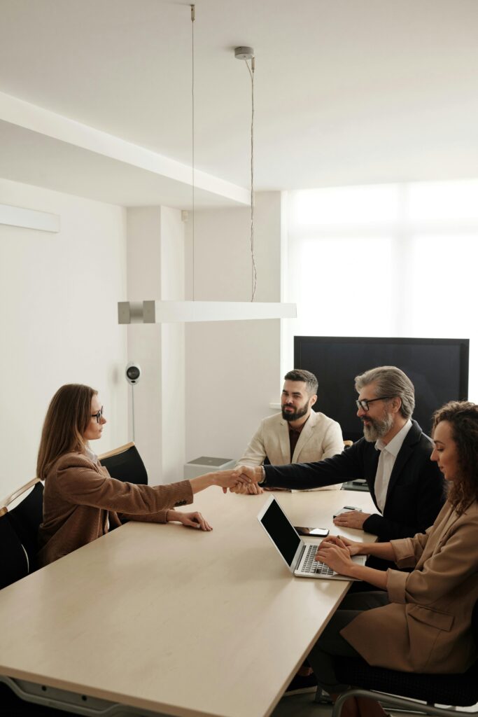 pexels-photo-4342493-4342493 Business professionals engaging in a handshake across a conference table, signifying successful collaboration.